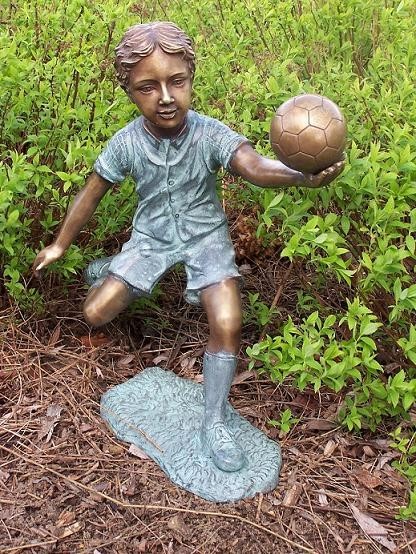 Junge Liam spielt Ball als Bronzeskulptur