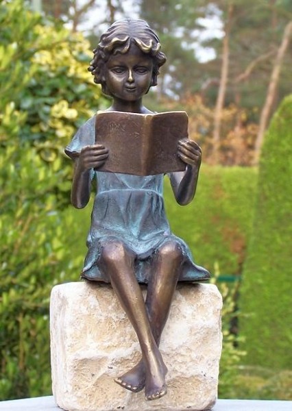 Mädchen Linda in Kleid mit Patina sitzend liest Buch als Bronzeskulptur